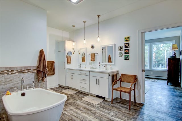 bathroom with vanity, a bathtub, hardwood / wood-style floors, and baseboard heating