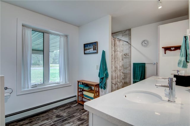 bathroom featuring a shower with shower curtain, baseboard heating, hardwood / wood-style flooring, and vanity