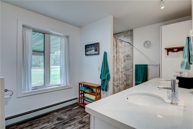6030 Mitchell Rd, Iron River, WI 54847 - full bathroom featuring a sink, a shower with curtain, wood finished floors, a baseboard heating unit, and double vanity