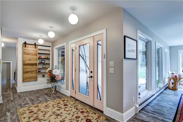 entryway featuring dark wood-type flooring, a barn door, and a baseboard heating unit