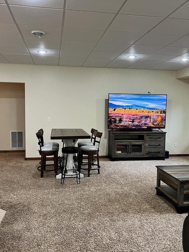 carpeted living room featuring a drop ceiling