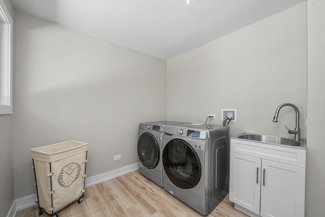 laundry area with sink, independent washer and dryer, light hardwood / wood-style floors, and cabinets