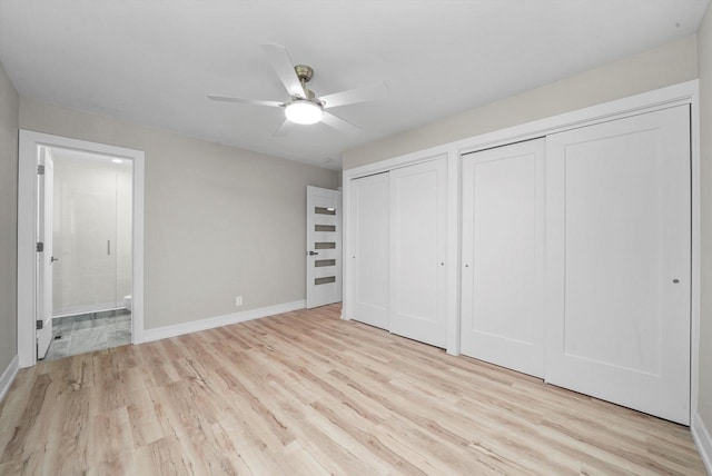 unfurnished bedroom with light hardwood / wood-style floors, multiple closets, ensuite bathroom, and ceiling fan