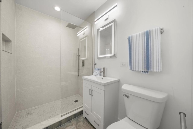 bathroom with vanity, a tile shower, and toilet