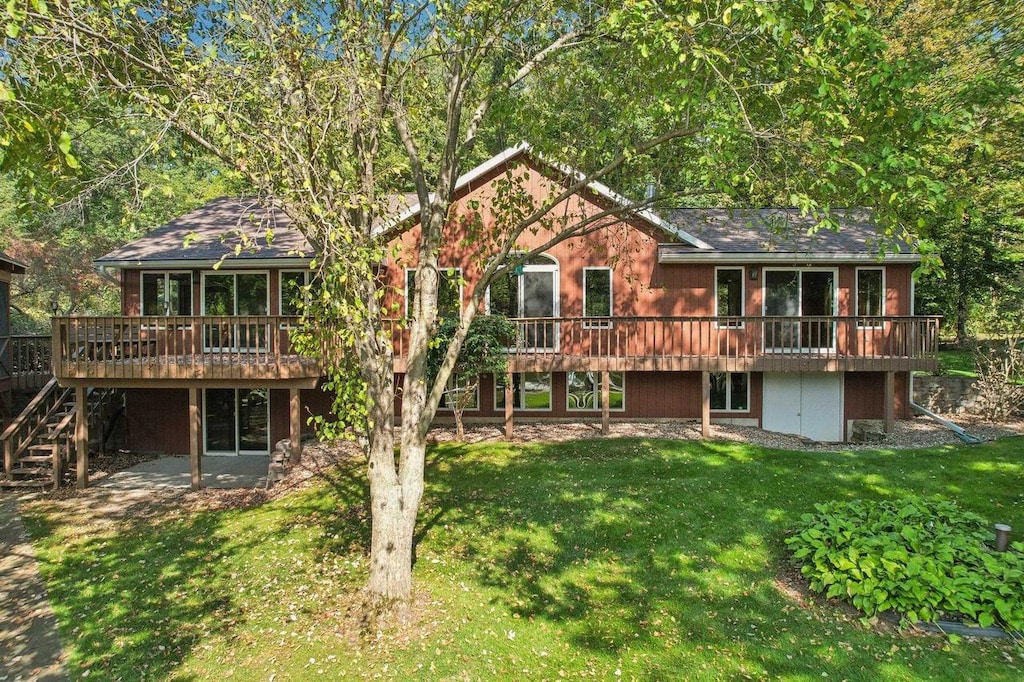 rear view of property featuring a deck and a lawn