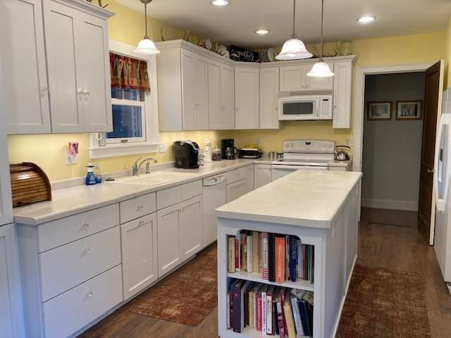 kitchen featuring dark wood-type flooring, white cabinets, white appliances, pendant lighting, and sink