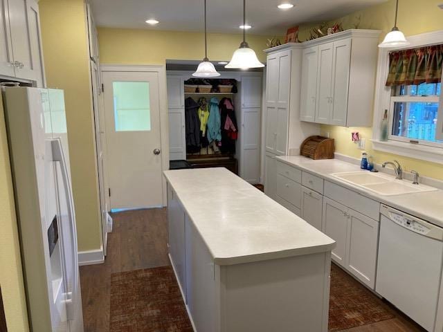 kitchen featuring white cabinets, white appliances, hanging light fixtures, and sink