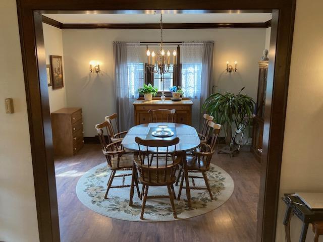 dining room with wood-type flooring, crown molding, and a chandelier