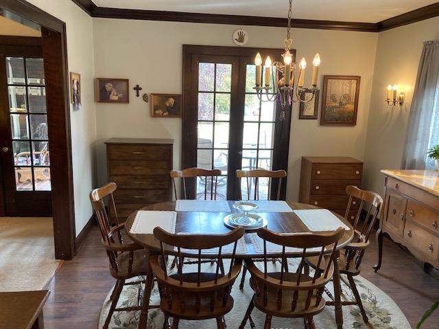 dining area featuring ornamental molding, a notable chandelier, and dark wood-type flooring