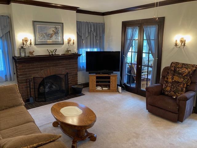 living room with carpet floors, crown molding, and a fireplace