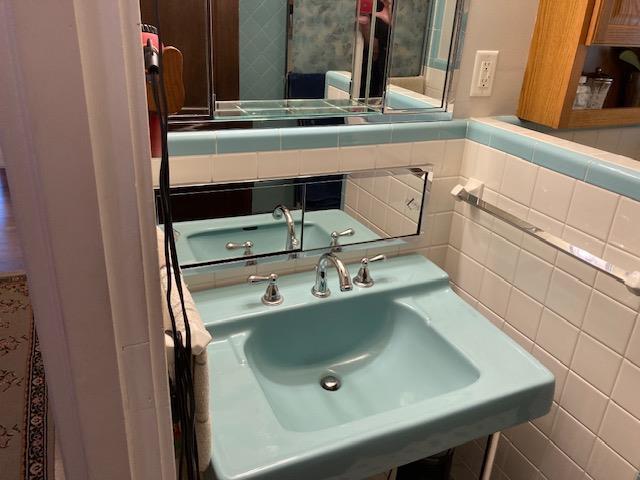 bathroom featuring backsplash, tile walls, and sink