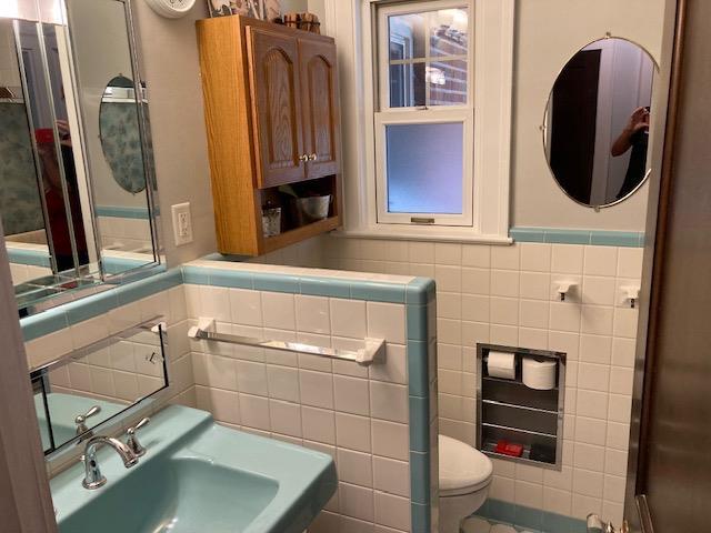 bathroom with tile walls, toilet, and sink