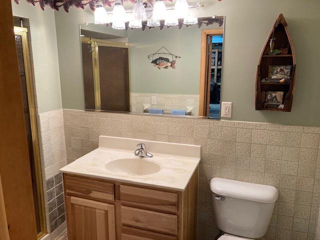 bathroom featuring vanity, tile walls, and toilet