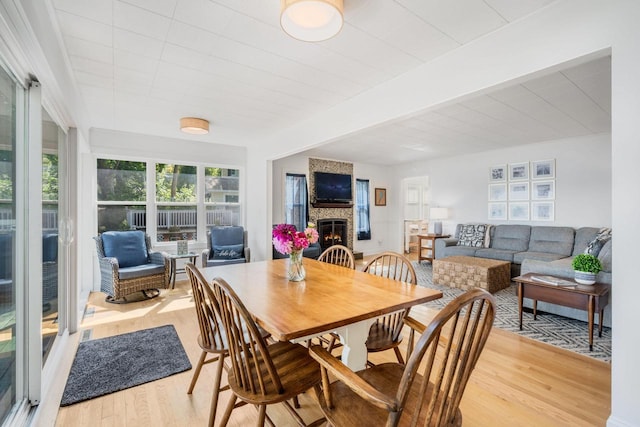 dining room with beamed ceiling, hardwood / wood-style flooring, and a fireplace