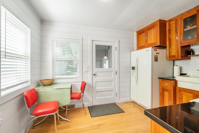 kitchen with a wealth of natural light, white refrigerator with ice dispenser, light wood-type flooring, and tasteful backsplash