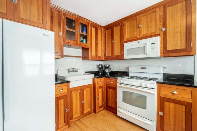 kitchen featuring sink, backsplash, light hardwood / wood-style floors, and white appliances