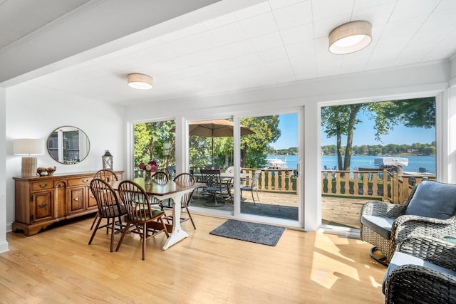 dining room with light hardwood / wood-style flooring, crown molding, and a water view