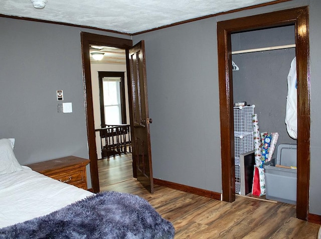 bedroom with a closet, hardwood / wood-style floors, and crown molding