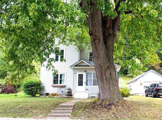 view of front facade with a garage, a front lawn, and an outbuilding