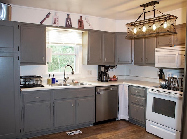 kitchen featuring gray cabinets, sink, white appliances, decorative light fixtures, and dark hardwood / wood-style flooring