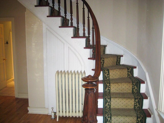 staircase with radiator heating unit and hardwood / wood-style flooring