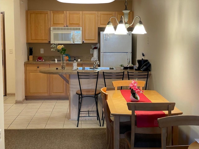 kitchen with pendant lighting, light tile patterned floors, white appliances, light brown cabinetry, and a notable chandelier