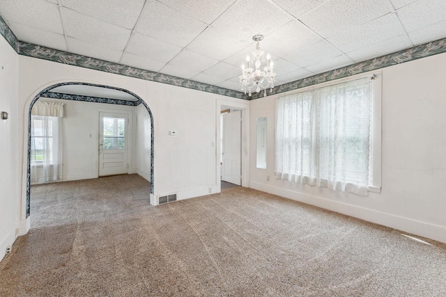 spare room with carpet floors, an inviting chandelier, and a paneled ceiling