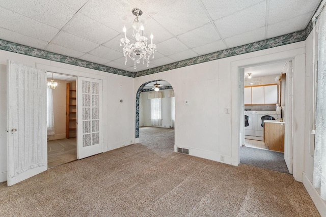 carpeted empty room with ceiling fan with notable chandelier, a drop ceiling, and washing machine and clothes dryer