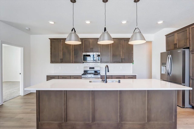 kitchen featuring a center island with sink, decorative light fixtures, sink, and appliances with stainless steel finishes