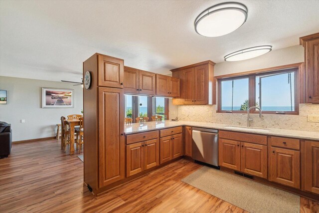 7001 Novak Rd, Racine, WI 53402 - kitchen featuring stainless steel dishwasher, a sink, light wood-style floors, decorative backsplash, and brown cabinets