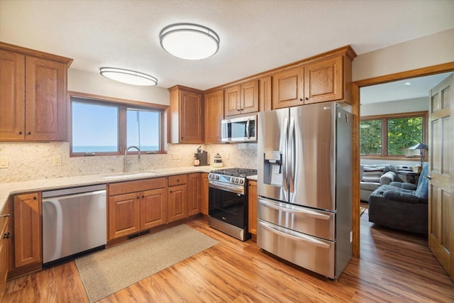7001 Novak Rd, Racine, WI 53402 - kitchen with stainless steel appliances, a sink, light wood-style flooring, brown cabinets, and tasteful backsplash