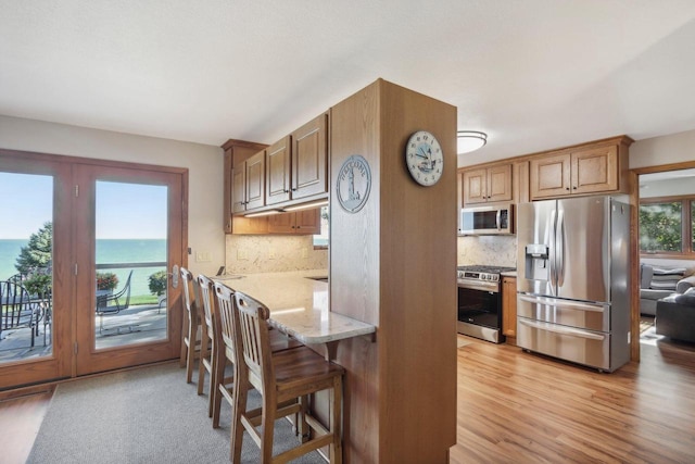 7001 Novak Rd, Racine, WI 53402 - kitchen with appliances with stainless steel finishes, light wood-style floors, backsplash, and light stone counters