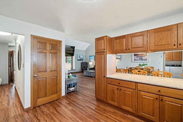 7001 Novak Rd, Racine, WI 53402 - kitchen with washer and dryer, brown cabinetry, light wood finished floors, and light stone countertops