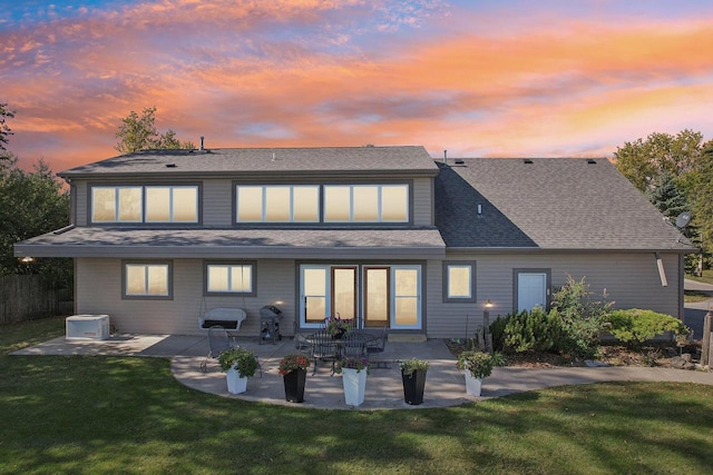 7001 Novak Rd, Racine, WI 53402 - back of house at dusk featuring a lawn, a patio, and roof with shingles