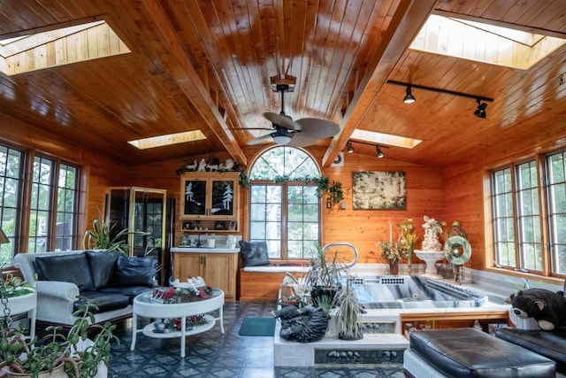 kitchen with lofted ceiling with skylight, track lighting, wooden walls, ceiling fan, and plenty of natural light