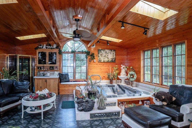 kitchen featuring kitchen peninsula, track lighting, vaulted ceiling with skylight, ceiling fan, and wooden walls