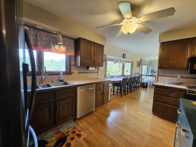 kitchen with light hardwood / wood-style floors, sink, decorative backsplash, black appliances, and ceiling fan