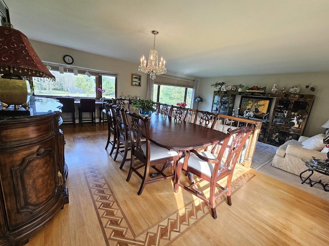 dining space with light hardwood / wood-style floors and a notable chandelier