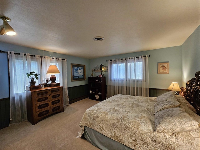 bedroom featuring carpet, wood walls, and a textured ceiling