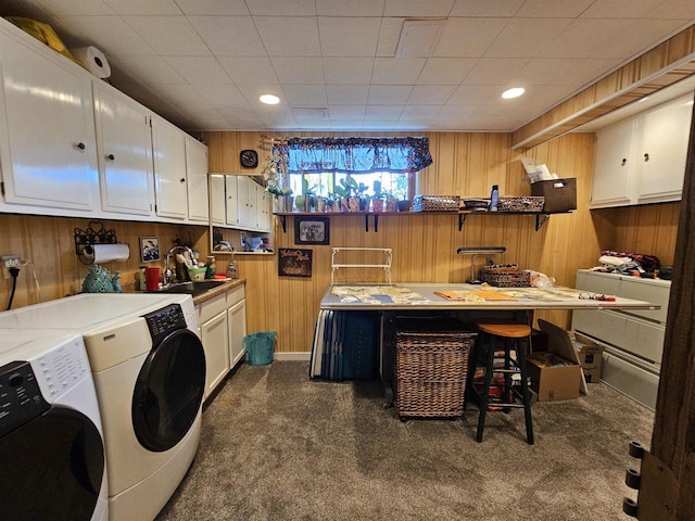 washroom featuring washing machine and clothes dryer, dark colored carpet, wood walls, and sink