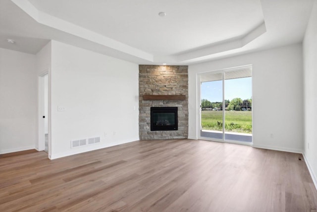 508 Hickory Hollow Rd Unit 0202, Waterford, WI 53185 - unfurnished living room featuring a stone fireplace, light hardwood / wood-style floors, and a tray ceiling