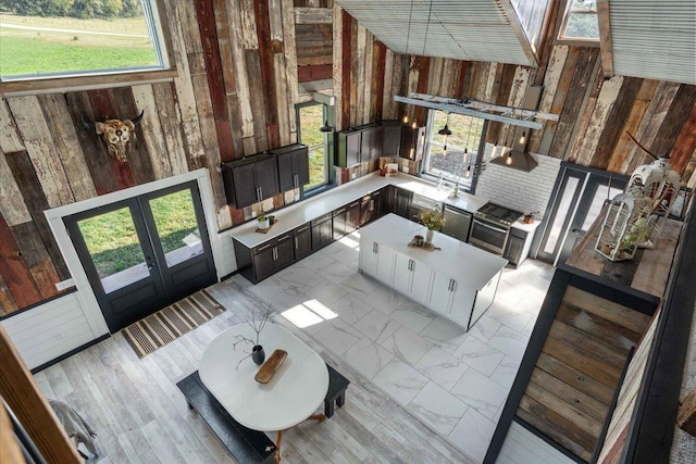 living room with a towering ceiling, wooden walls, and french doors