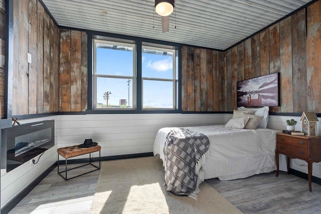 bedroom with wooden ceiling, light hardwood / wood-style floors, and wood walls