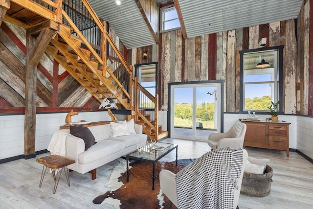 sitting room featuring a towering ceiling, light hardwood / wood-style flooring, and wooden walls