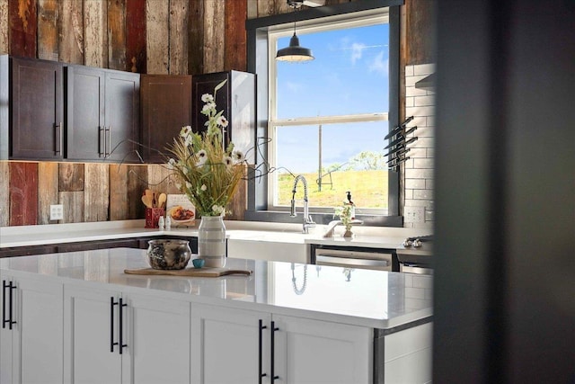 kitchen featuring white cabinetry, dishwasher, sink, and decorative light fixtures