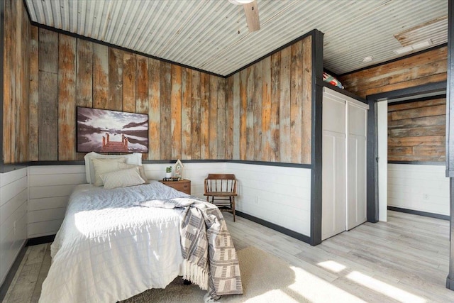 unfurnished bedroom with wood ceiling, ceiling fan, wooden walls, and light hardwood / wood-style floors