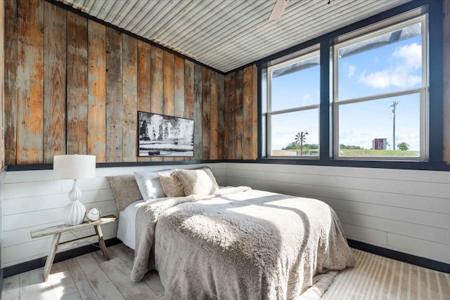 bedroom featuring light wood-type flooring, wood ceiling, and wooden walls