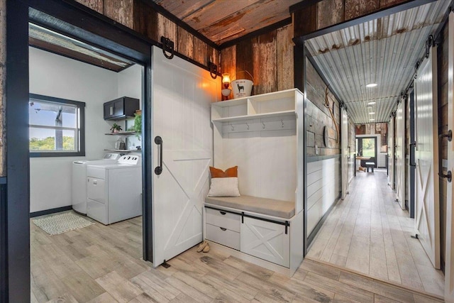 hallway featuring a barn door, separate washer and dryer, and light wood-type flooring