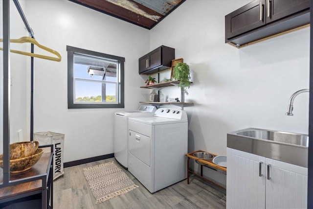 laundry area with independent washer and dryer, sink, light hardwood / wood-style flooring, and cabinets