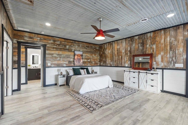 bedroom featuring wooden ceiling, wood walls, ceiling fan, and ensuite bathroom